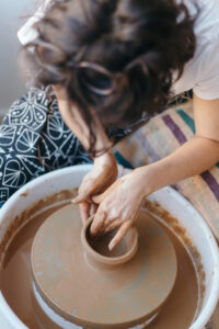 person throwing on the pottery wheel